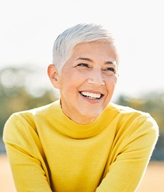 Woman with yellow shirt sitting outside and smiling