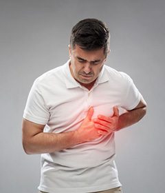 Man gripping his chest, experiencing heart problems