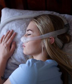 Sleeping woman wearing CPAP nasal mask