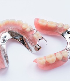 Partial dentures with metallic clips on white surface